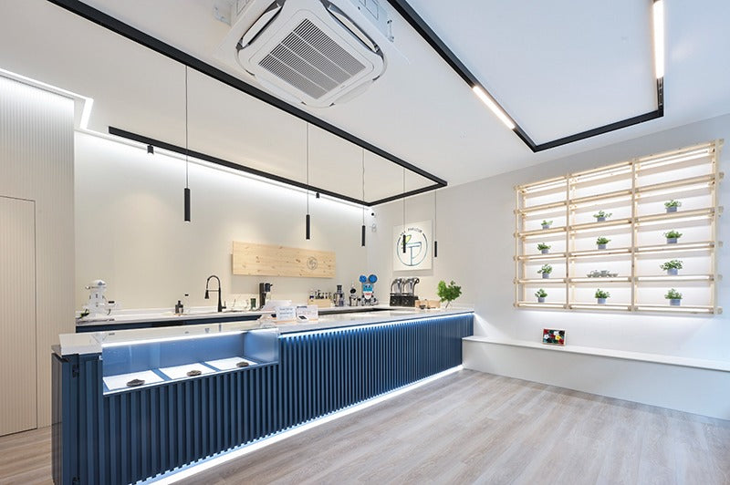 Tea Parlour’s modern matcha café interior near Trafalgar Square, featuring a sleek blue counter, minimalist shelving, and soft lighting.