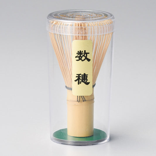 Bamboo whisk in a clear cylindrical container 