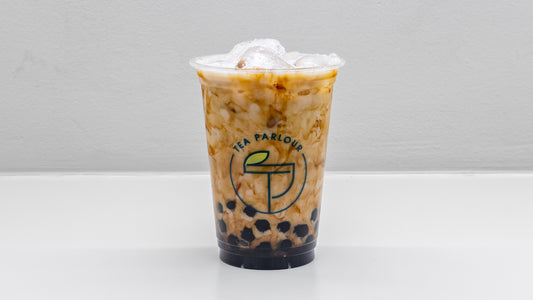 Oolong bubble milk tea with black tapioca pearls and ice in a clear Tea Parlour cup in central london